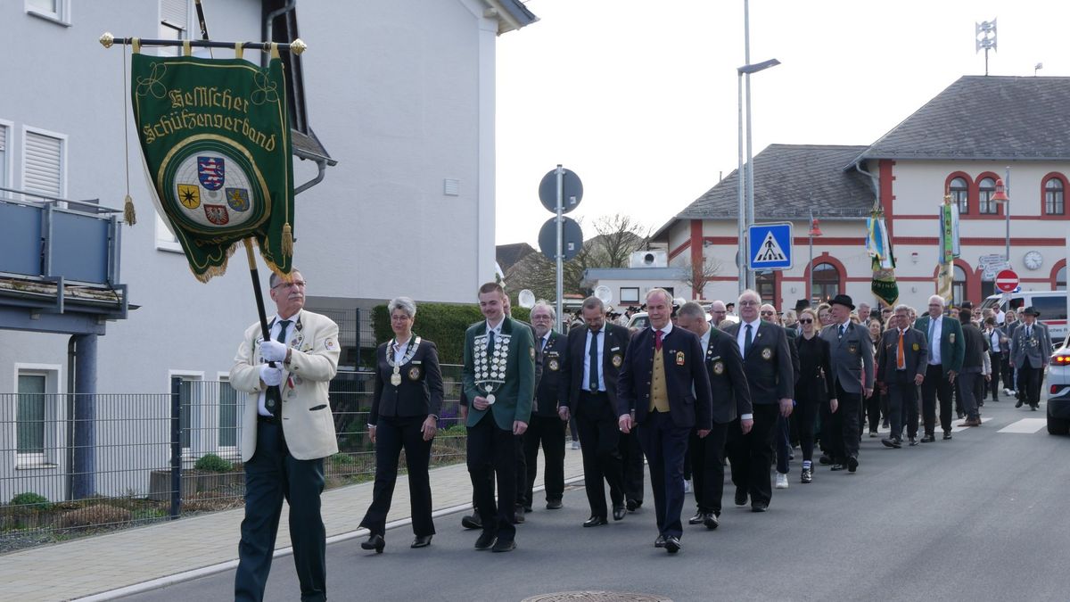 Ein Fahnenträger in weißer Jacke vor einer festlichen Marschgruppe, die als Delegation beim Festumzug teilnahm.