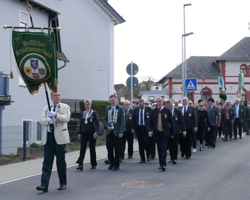 Ein Fahnenträger in weißer Jacke vor einer festlichen Marschgruppe, die als Delegation beim Festumzug teilnahm.