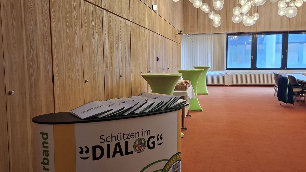 Blick in einen Raum mit einer Theke, auf der Logo des Projekts "Schützen im Dialog" zu sehen ist.